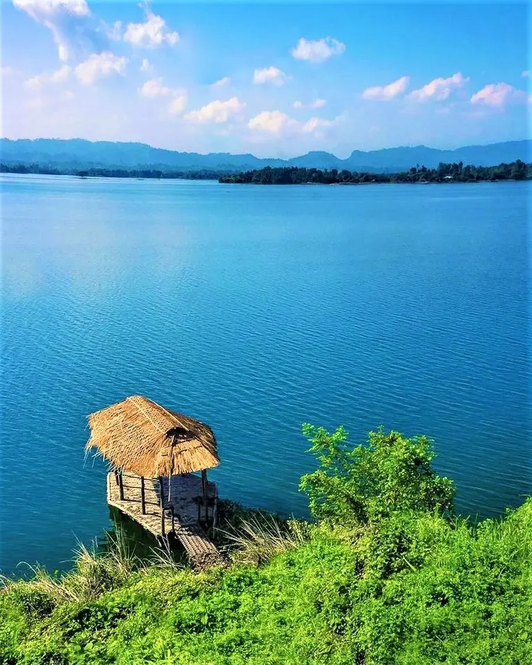 Serene blue waters of Kaptai Lake in Rangamati, surrounded by rolling green hills and floating fishing nets.