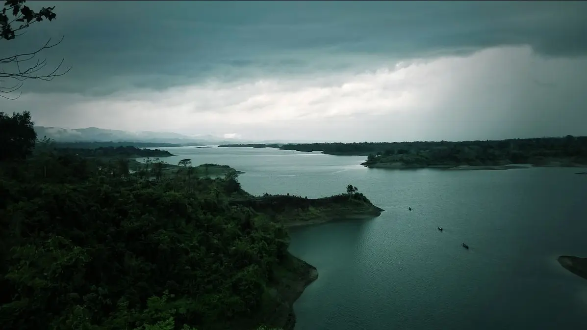 Kayaking and scenic greenery at Mohamaya Lake in Mirsharai, showing the peaceful water and surrounding rubber plantation hills.