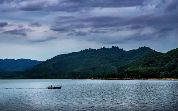 A wide view of the Karnaphuli River in Chittagong, featuring local boats and the industrial backdrop of the port city.
